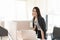 Smiling female executive leaning on desk in office