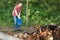 Smiling female farm worker feeding stuff to chickens