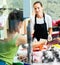 Smiling female fishmonger offering fresh fish and seafoods for sale in shop