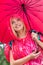 Smiling female hiker in red raincoat holding umbrella