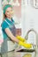 Smiling female housekeeper rinsing dishes