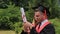 Smiling female and male graduates holding diplomas and taking selfie on phone