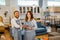 smiling female and male shop assistants in aprons carrying a tablet