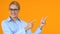 Smiling female manager pointing fingers into orange background template for text