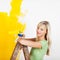 Smiling female painting yellow