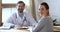 Smiling female patient looking at camera visiting male doctor, portrait