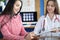 Smiling female patient signs medical form at clinic meeting with doctor