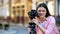 Smiling female photographer focusing camera objective on street, photo shooting