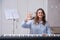 Smiling female pianist showing hand gesture of greeting, online music lessons on electric piano at home