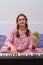 Smiling female pianist sitting on home bed with euro money in hands