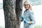 smiling female scientist in eyeglasses putting sample of bark of tree by tweezers in jar