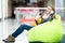 Smiling female sitting in bean bag in office or shopping center