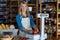 Smiling female staff weighting vegetables on scale in supermarket