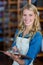 Smiling female staff writing on clipboard in supermarket