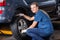 Smiling Female Technician Adjusting Car Tire