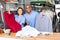 Smiling female worker of modern laundry standing with her colleague at reception counter, showing clean clothing and