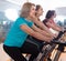 Smiling females riding stationary bicycles