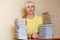 Smiling fifty-year-old woman in a yellow sweater sitting at a table with books