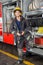 Smiling Fireman Standing By Truck At Fire Station