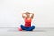 Smiling fit caucasian woman in sportswear sits on the mat with cross-legged and put her hair up in a bun before workout