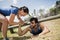 Smiling fit woman helping man crawling under the net during obstacle course