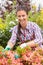 Smiling florist arranging flowers in garden center