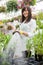 Smiling Florist Watering Plants In Greenhouse