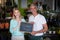 Smiling florists holding flower shop sign on slate in flower shop