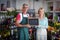 Smiling florists holding open sign on slate in flower shop