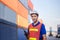 Smiling foreman in hardhat and safety vest talks on two-way radio control loading containers box from cargo