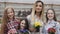 Smiling four girls with flowerpots in hands looking at camera