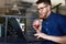 Smiling freelancer man with plastic cup of fresh beverage in hand works with laptop. Businessman in glasses drinks juice