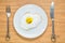 Smiling fried egg lying on a wooden cutting board with morning inscription near it. Classic Breakfast concept.