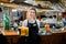 Smiling friendly waitress serving a pint of draft beer in a pub. Portrait of happy young woman serving beer in bar