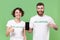 Smiling friends couple in volunteer t-shirt isolated on green background. Voluntary free work assistance help charity
