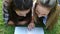 Smiling friends lying on the grass while using a laptop