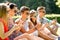 Smiling friends with smartphones sitting on grass