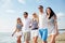 Smiling friends in sunglasses walking on beach