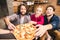 Smiling friends tasting pizza while sitting