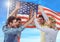 Smiling friends throwing up their hands against fluttering american flag background