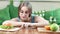 Smiling funny young woman playing fingers on table choosing between healthy and unhealthy food