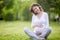 Smiling future mom sitting cross-legged on grass lawn