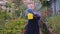 Smiling gardener young guy while holding a sprinkler playing a bit then posing in front of the camera in a large