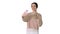 Smiling and gesturing young woman having video call on her phone while walking on white background.