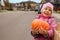 Smiling girl bears pumpkin in hands