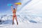 Smiling girl in bikini holding snowboard above head