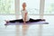 Smiling girl child practicing yoga, , working out wearing sportswear, indoor full length, in front of panoramic window