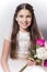 Smiling girl with communion dress holding bouquet of peonies.