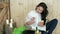 Smiling girl decorating easter eggs, candles light on old stumps, wooden basket full of tiny rabbits