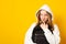 Smiling girl dressed white hoodie on yellow background with backpack. Positive cool schoolgirl with backpack